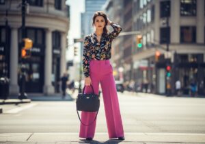 Młoda kobieta na ulicy w szerokich spodniach i bluzce, naturalne światło, miejski styl, pewna siebie poza