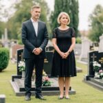Średniowieczny mężczyzna i kobieta przy grobie na cmentarzu, wyrażający szacunek i zadumę.